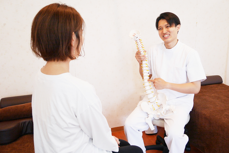 女性のお客様に骨格標本を使いながら施術の方針を説明している写真
